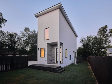 Back of property at dusk with stone siding, a fenced backyard, stucco siding, and a wooden deck