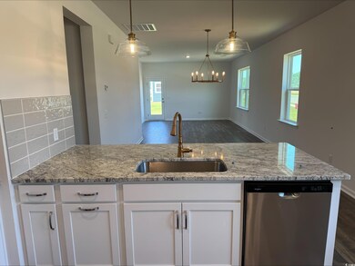 Kitchen with dishwasher, a sink, white cabinetry, and light stone counters