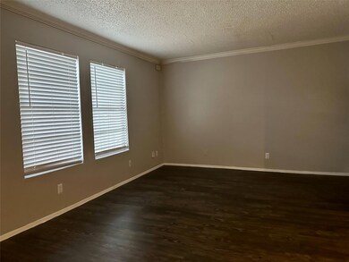 Unfurnished room featuring crown molding, a textured ceiling, and dark wood-style floors