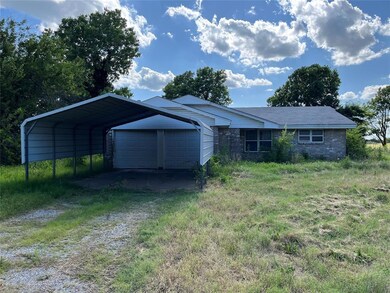 View of front of property with dirt driveway and brick siding