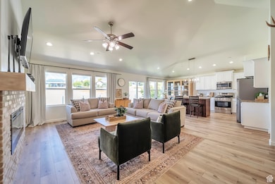 Living area with lofted ceiling, a chandelier, light wood-type flooring, recessed lighting, and a fireplace