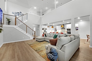 Living room featuring light wood finished floors, a towering ceiling, and stairway