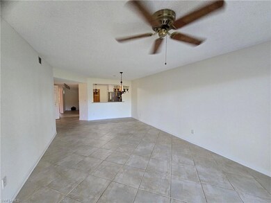 Unfurnished living room with ceiling fan with notable chandelier, a textured ceiling, and light tile patterned flooring