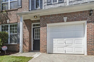 Entrance to property featuring brick siding, a garage, and driveway