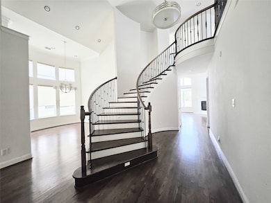 Stairs with a chandelier, wood finished floors, a high ceiling, a fireplace, and recessed lighting