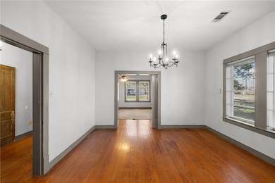Unfurnished dining area with a chandelier, dark wood finished floors, healthy amount of natural light, and a ceiling fan