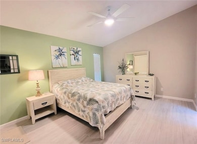 Bedroom with vaulted ceiling, light wood finished floors, and a ceiling fan