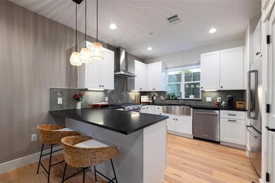 Kitchen featuring a peninsula, wall chimney range