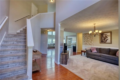 Living area featuring wood finished floors, a chandelier, stairway, ornamental molding, and a textured ceiling