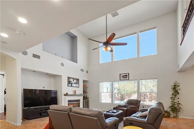 Living room with ceiling fan, a warm lit fireplace