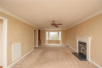 The large living room, located to the right of the entry way, has a fireplace, a ceiling fan and built in shelving