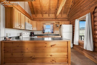 Kitchen with white appliances, wooden ceiling, a peninsula, dark countertops, and rustic walls