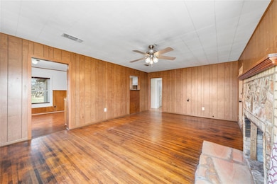 Living room with panelling, ceiling fan, a firepla