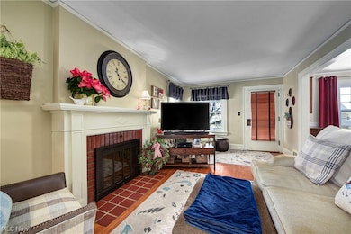 Living room with dark hardwood / wood-style floors, a brick fireplace, and ornamental molding