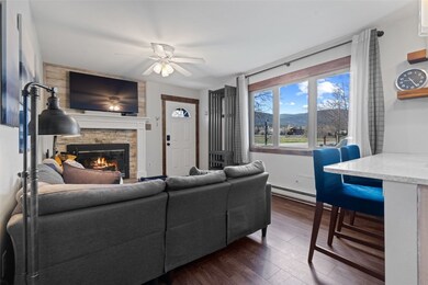 Living room with a stone fireplace, ceiling fan, a