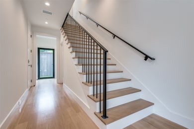 Stairway with wood finished floors and recessed lighting