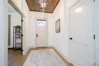 Entryway with wood ceiling, light wood-style flooring, and a chandelier