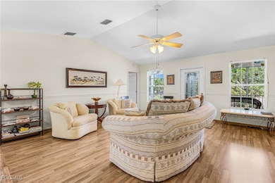 Living area featuring ceiling fan, light wood finished floors, and vaulted ceiling
