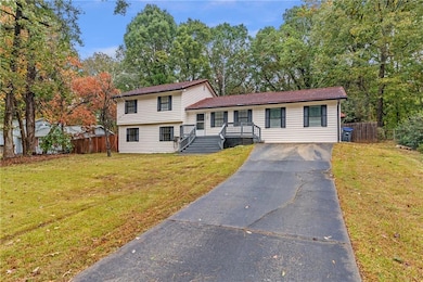 Tri-level home with driveway, view of scattered trees, and a tiled roof