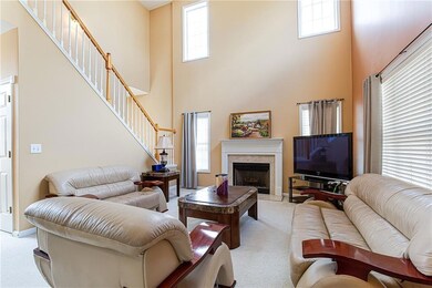 Living room featuring a high ceiling, light colored carpet, and a healthy amount of sunlight