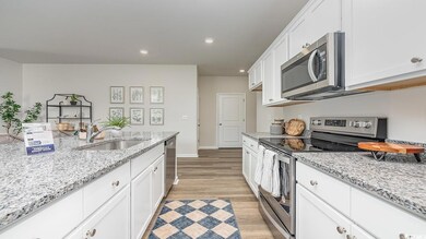 Kitchen with sink, appliances with stainless steel finishes, white cabinets, and light stone counters