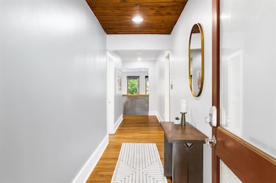 Hallway featuring light wood finished floors, bas