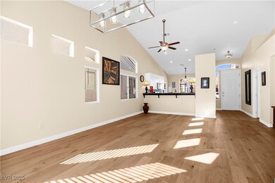 Unfurnished living room with a chandelier, light wood-type flooring, high vaulted ceiling, recessed lighting, and ceiling fan