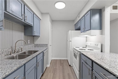 Kitchen featuring under cabinet range hood, visible vents, a sink, white electric range oven, and light wood-style floors