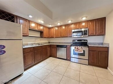 Kitchen featuring a sink, brown cabinets, light ti