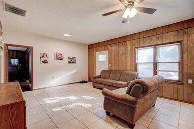 Living room featuring ceiling fan, wood walls, and