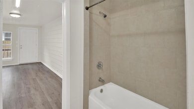 Bathroom featuring washtub / shower combination and wood finished floors