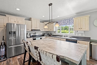 Kitchen featuring stainless steel appliances, under cabinet range hood, ornamental molding, a kitchen bar, and dark wood finished floors
