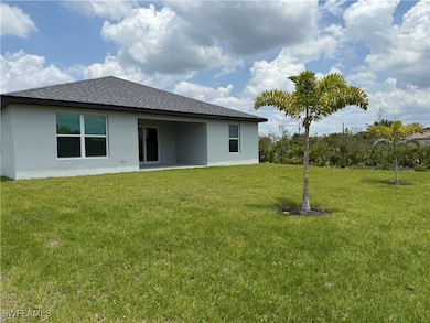 Rear view of property featuring a yard, roof with