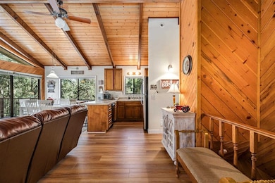 Living room featuring ceiling fan, vaulted ceiling with beams, wood-type flooring, and wood ceiling