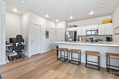 Kitchen featuring appliances with stainless steel finishes, a kitchen bar, light wood-type flooring, white cabinets, and a desk