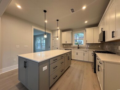 Kitchen featuring decorative backsplash, gas range, light wood-style flooring, white cabinetry, and recessed lighting