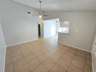 Spare room with vaulted ceiling, light tile patterned flooring, and a textured ceiling