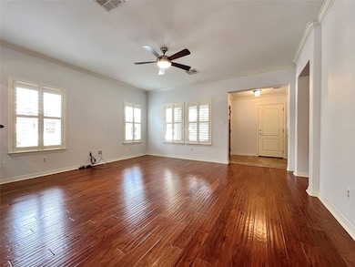 Unfurnished living room featuring ornamental molding, dark wood-style flooring, and ceiling fan