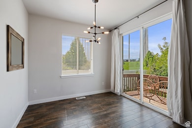Spare room with a chandelier and dark wood-style floors