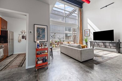 Living room with healthy amount of natural light, finished concrete floors, and a high ceiling