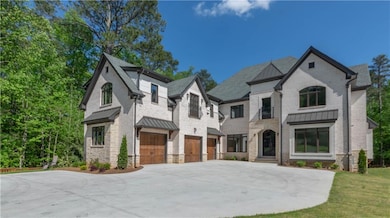 French country style house with metal roof, a garage, driveway, and a standing seam roof