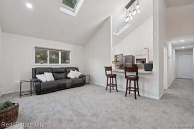 Living room with a skylight, light carpet, high vaulted ceiling, and recessed lighting