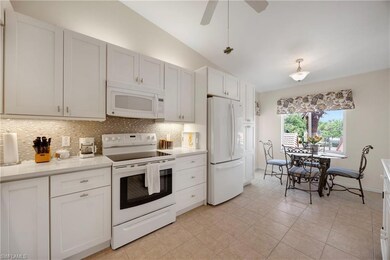 Kitchen with white appliances, tasteful backsplash, light countertops, vaulted ceiling, and light tile patterned flooring