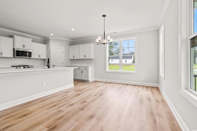 Kitchen with stainless steel microwave, a chandelier, healthy amount of natural light, light wood finished floors, and recessed lighting