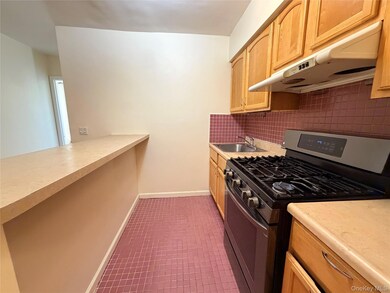 Kitchen featuring gas stove, under cabinet range hood, light countertops, decorative backsplash, and light brown cabinets