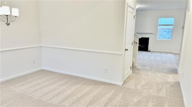Unfurnished room featuring light colored carpet and a chandelier
