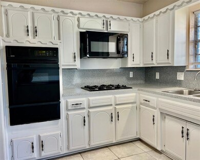 Kitchen with white cabinets, backsplash, light til