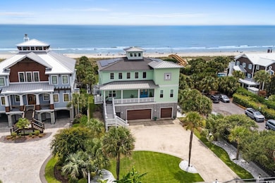 View of front facade featuring curved driveway, view of water and beach, an attached garage, stairway, and a metal roof