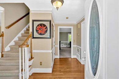 Foyer entrance with stairway, ornamental molding, and wood finished floors