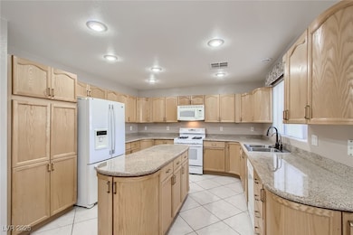 Kitchen with visible vents, light brown cabinetry,